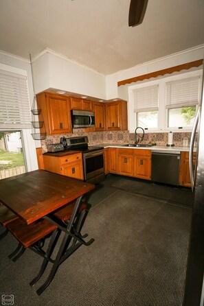 A kitchen with wooden cabinets, a microwave, a stove, and a sink.