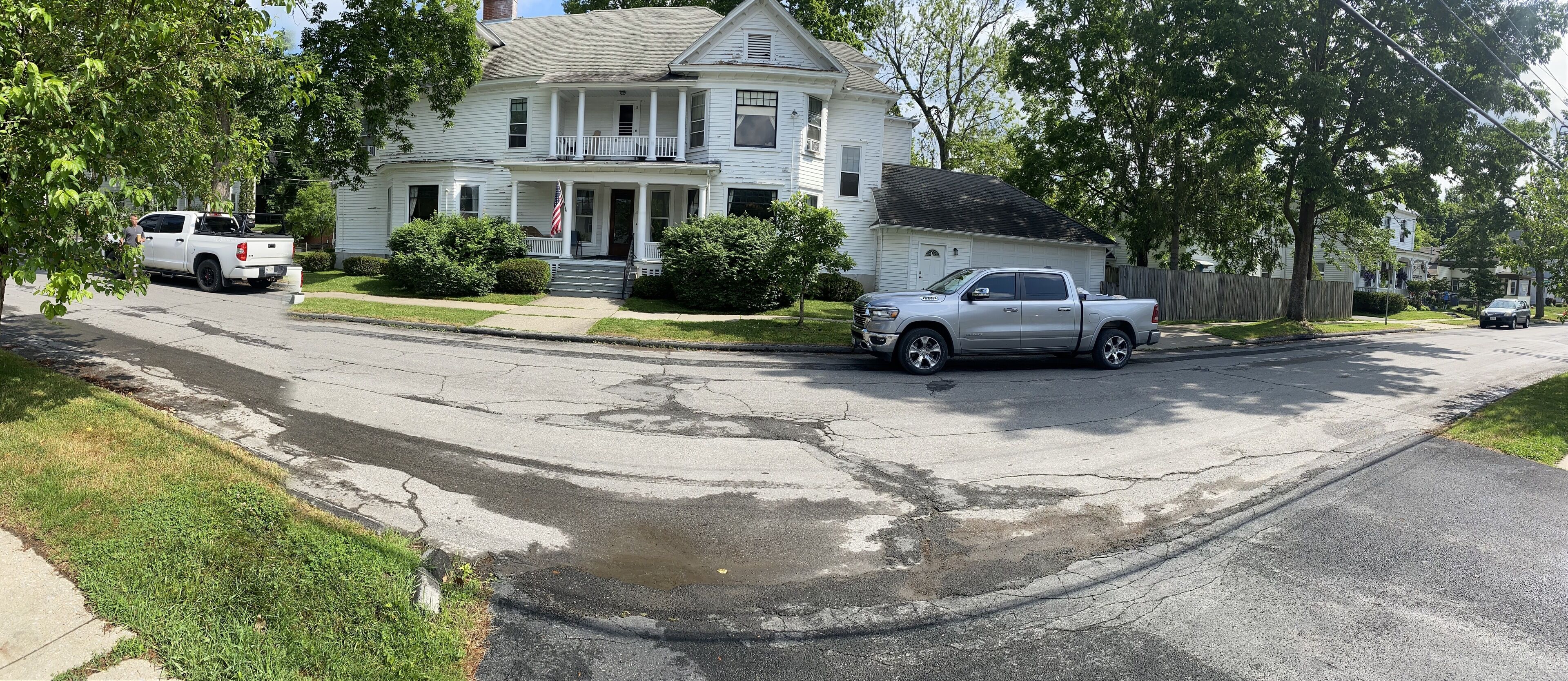 A two-story house with a front porch, a driveway, and a street.