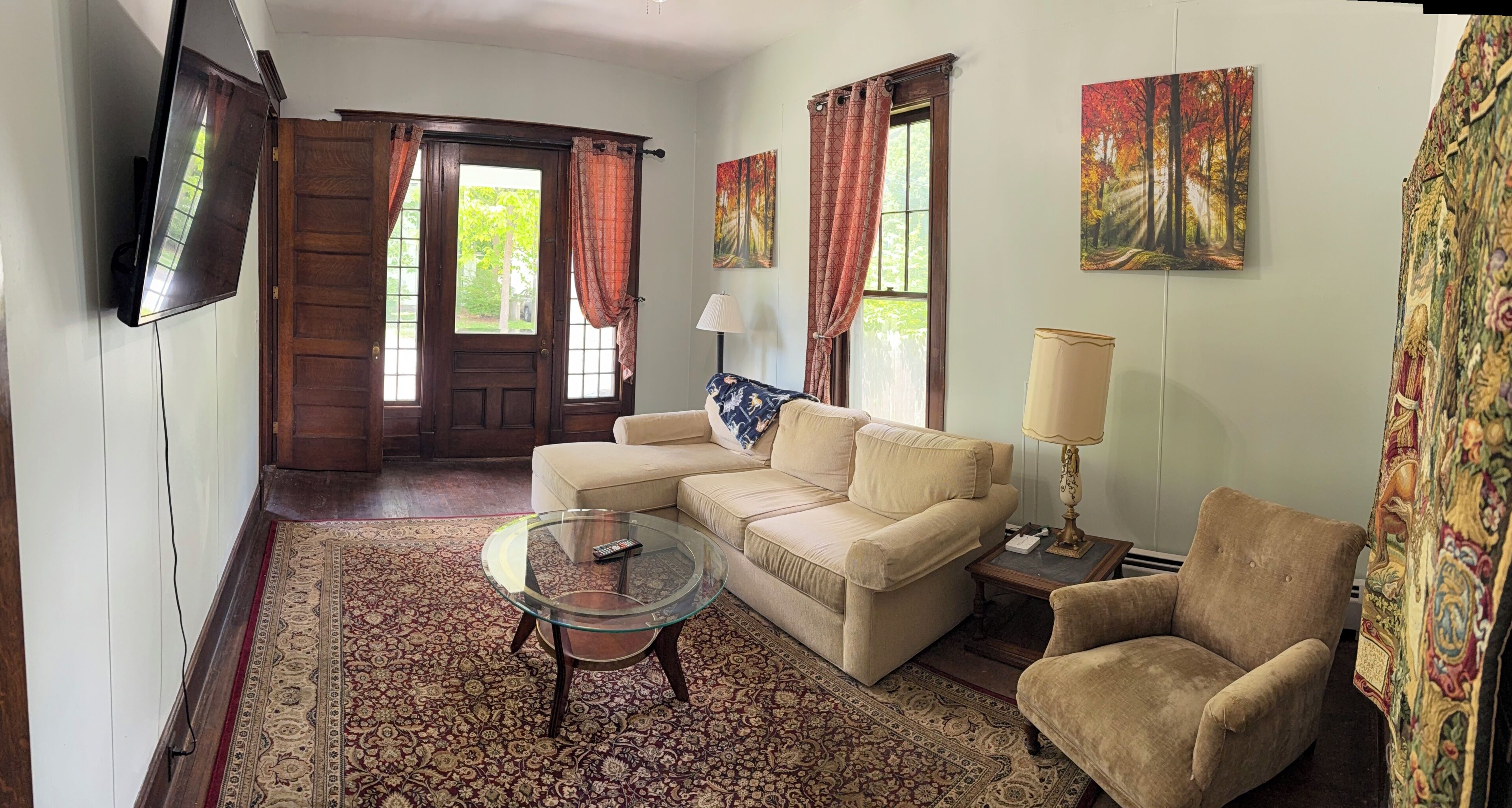Un salon comprenant un canapé, un fauteuil, une table basse en verre et un tapis à motifs.
