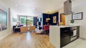 A modern living room with a dining area, a kitchen with a built-in oven, and a large window offering a view of the outdoors. - Centrally Located Modern Luxury, Walking Distance to UCLA, Westwood (Los Angeles)