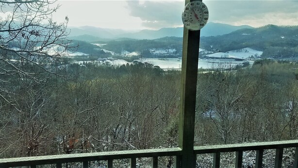 A view from a balcony with a wooden railing, overlooking a snow-covered landscape with mountains and a body of water in the distance. - A Little Slice of Smokey Mtn. Heaven - with WIFI (Franklin)