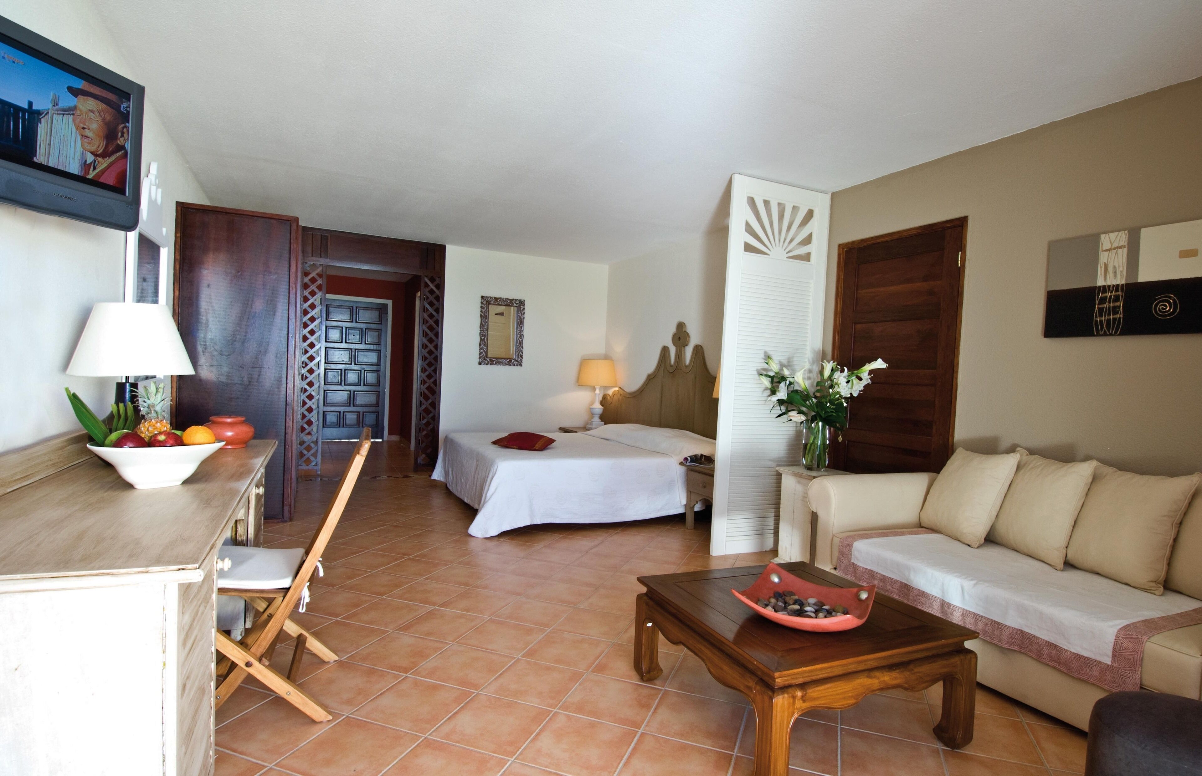 Une chambre d’hôtel avec un lit, un canapé, une table à manger, une télévision et une porte de salle de bain.