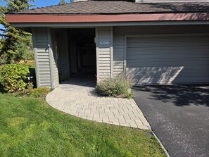 A residential building with a garage door, a driveway, and a small garden area. - Snowcreek Resort Vacation Rental 506 (Mammoth Lakes)
