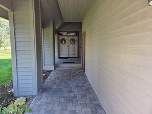 A covered walkway leading to a double door with a decorative glass design, flanked by siding walls. - Snowcreek Resort Vacation Rental 506 (Mammoth Lakes)
