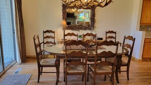 Een eetgedeelte met een ronde tafel, omringd door houten stoelen met beklede zitplaatsen.