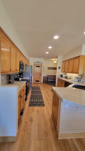 A kitchen with wooden cabinets, a central island, and a microwave. - Snowcreek Resort Vacation Rental 506 (Mammoth Lakes)