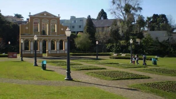 A building with a classical architectural style, surrounded by a well-maintained garden with manicured lawns and pathways.
