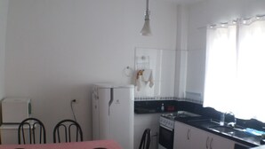 A compact kitchen with a dining area, featuring a refrigerator, stove, and a table with chairs.