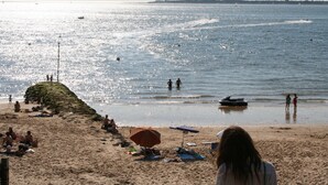 Una playa con gente, un jet ski y una costa distante.