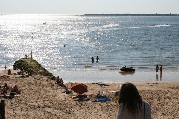 Een strand met mensen, een jetski en een verre kustlijn.