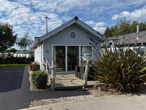 A small, single-story building with a porch, a circular window, and a door with glass panels.