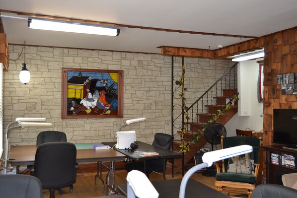 Una sala de conferencias con pared de piedra, un cuadro, una escalera de madera y un televisor.