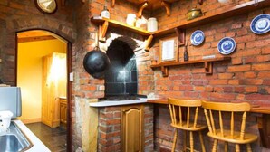 Une cuisine avec un mur en briques, des tabourets de bar en bois et un poêle noir.