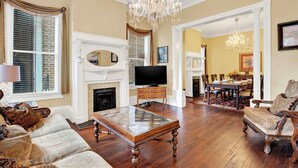 A spacious living room with a fireplace, a television, and a dining area with a chandelier.