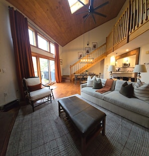 A spacious living room with a high ceiling, a dining area, and a kitchen.