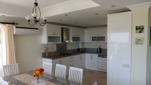 Une cuisine moderne avec des meubles blancs, des plans de travail en granit et un coin repas avec une table dressée pour quatre personnes.