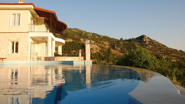 Vue sur une maison depuis la piscine, avec une montagne en arrière-plan.
