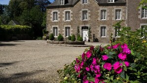 A stone building with multiple windows and a gravel driveway.