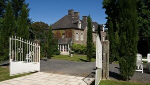 A gated entrance to a large, historic building with a stone facade and a small, attached structure with a gabled roof.