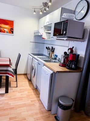 Uma cozinha compacta equipada com máquina de lavar, máquina de lavar louça, micro-ondas e cafeteira.