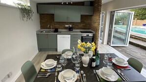 Uma cozinha moderna com armários cinzas, parede decorada com tijolos e área de jantar com mesa posta para quatro pessoas.