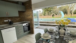 Cozinha moderna com máquina de lavar louça, cafeteira e vista para uma piscina.
