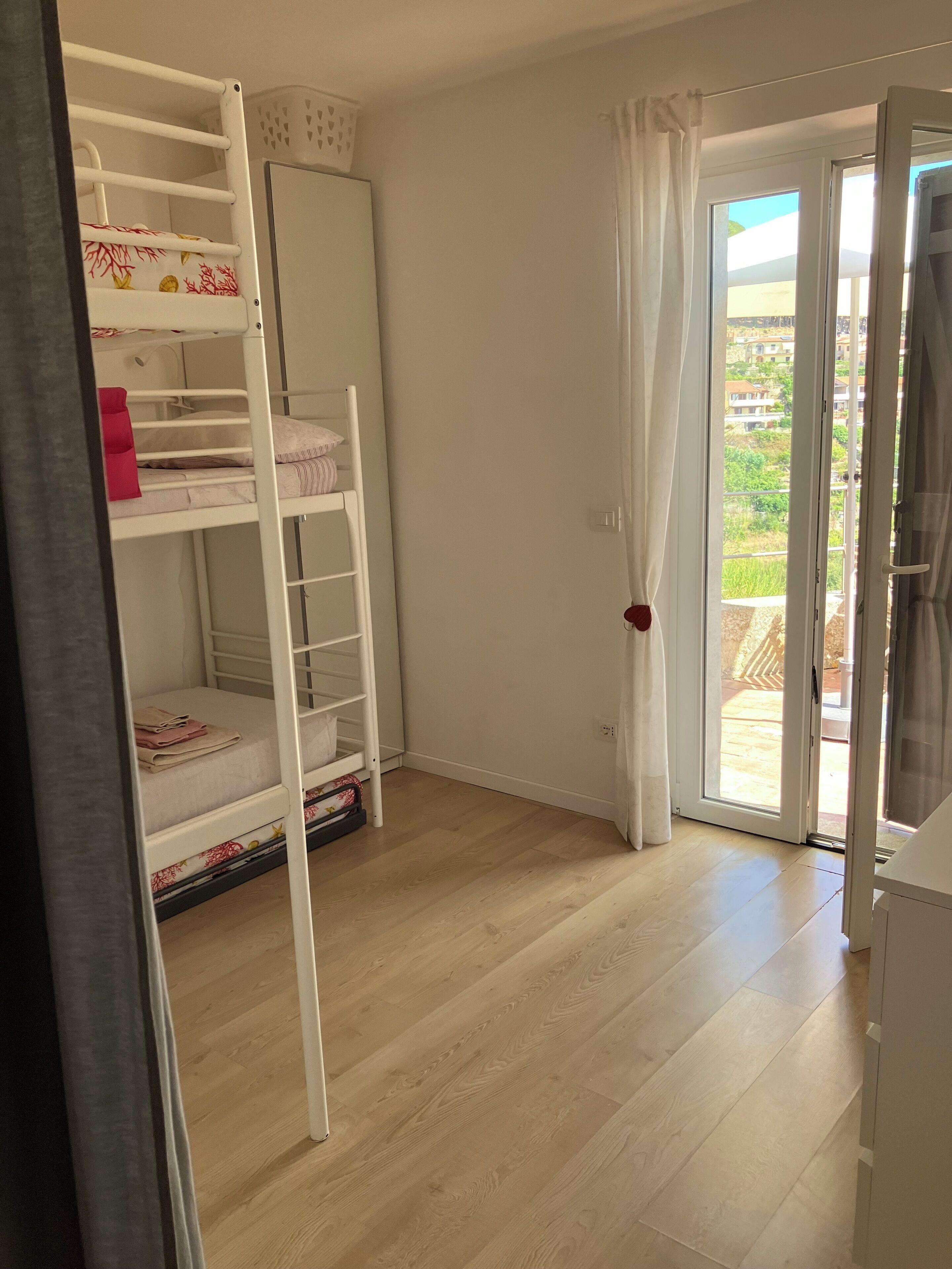 Una stanza con un letto a castello, un armadio e una porta scorrevole in vetro che dà su uno spazio all'aperto.