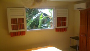 A room with a bed, a window with curtains, a wardrobe, and an air conditioning unit. - Bottom of villa for rent in diamond (F3) (Diamant)