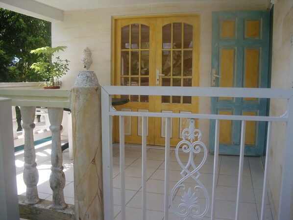 A white metal gate with a decorative design, a yellow door with glass panels, and a blue door with a geometric pattern.