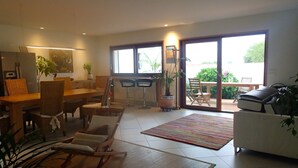 A spacious living room with a dining area, large sliding glass doors to a patio, and a grill outside.