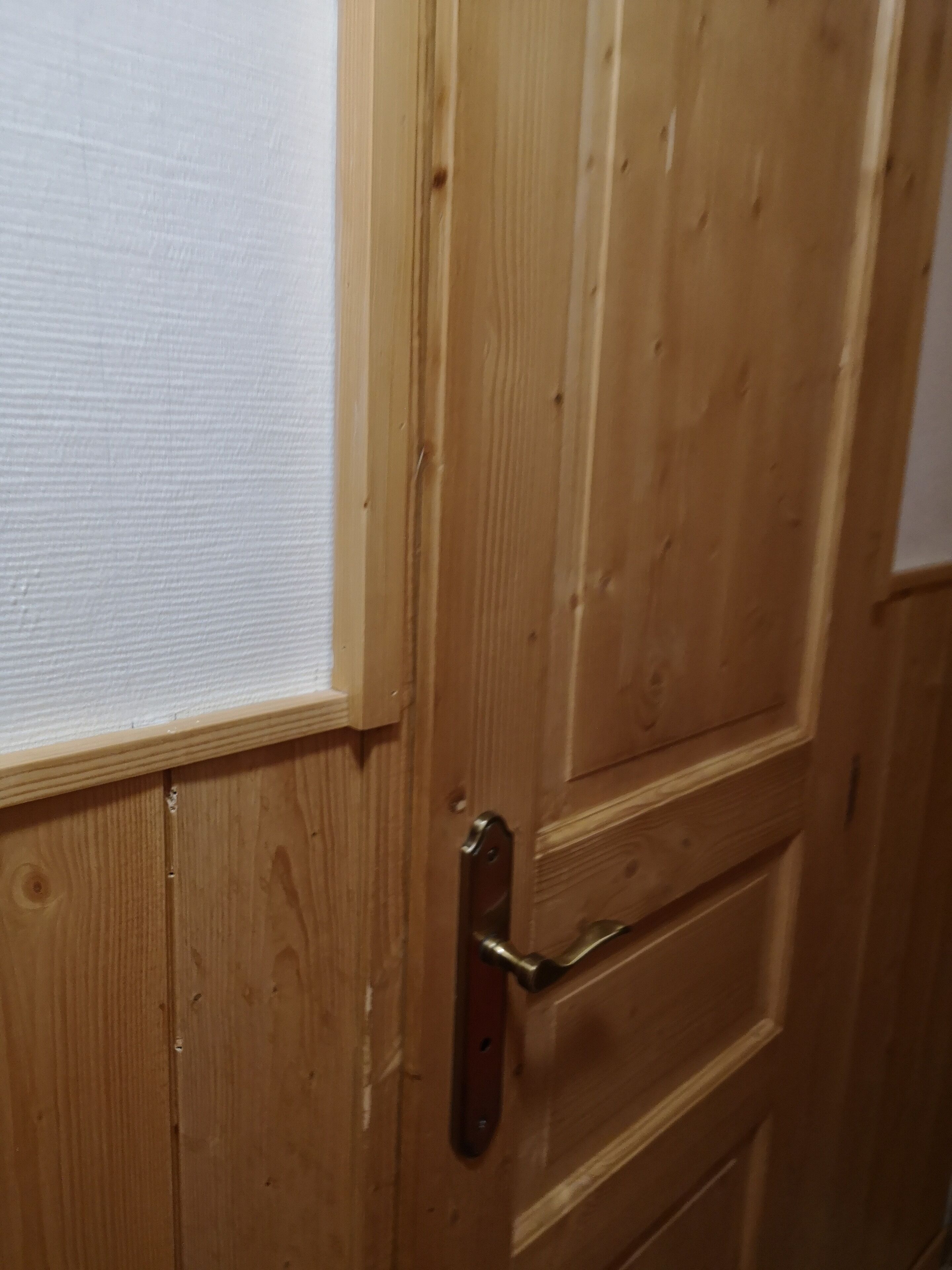 Une porte en bois avec une poignée en métal et un panneau à texture.