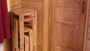 En interiör med träpanel, en tv som är monterad på väggen, en trädörr och ett litet träbord med hyllor.