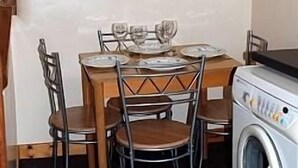 A compact kitchen with a wooden table set for two, a washing machine, and a chair. - Views Of The Clwydian Range, Nr Ruthin. Snowdonia 1hr. Local pub 1 mile (Rhewl)