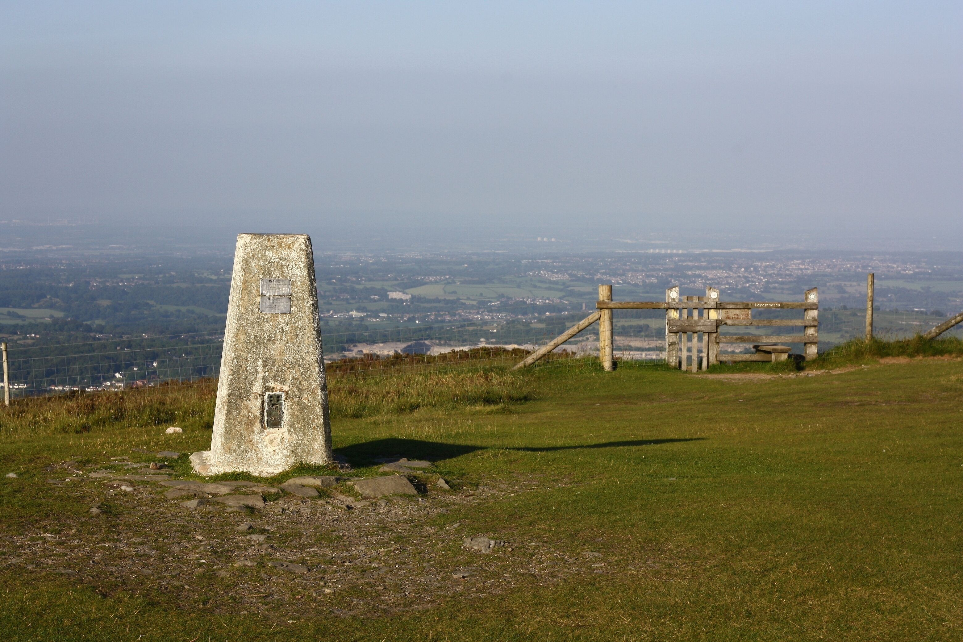 Un monument en pierre, avec une clôture en bois et un panneau en arrière-plan.