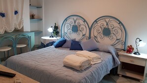 Een netjes ingerichte slaapkamer met een bed, nachtkastjes, een klein tafeltje met een lamp en een stoel.