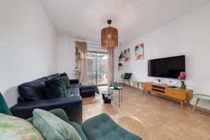 A modern living room with a leather sofa, a green armchair, a TV, and a wooden entertainment unit. - APARTMENT WITH COMMUNITY POOL. 400 METERS FROM THE BEACH. LARGE YARD. (Torrevieja)