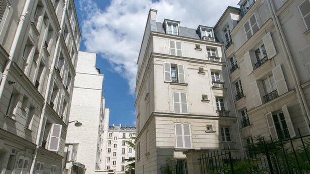 Eine enge Straße mit hohen Gebäuden, mit zahlreichen Fenstern und Balkonen.
