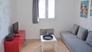 Ein modernes Wohnzimmer mit einem grauen Sofa, einer roten Unterhaltungseinheit, einem weißen Couchtisch und einem Fenster mit Blick.