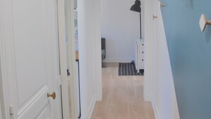 Ein Flur mit Holzboden, weißen Wänden und einer blauen Akzentwand. Links eine Tür, rechts eine Lampe und eine Deckenleuchte.