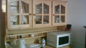 Una cocina con armarios de madera, microondas, hervidor y cafetera.