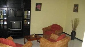 Una sala de estar con muebles de mimbre, un televisor y elementos decorativos en las paredes.