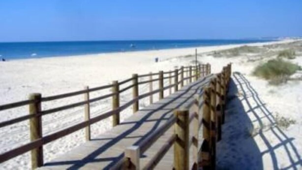 A wooden boardwalk leading to a sandy beach with clear blue skies. - Apartment in residence (Altura)