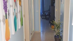 A hallway with light blue walls, a tiled floor, and a door leading to another room. - Apartment in residence (Altura)