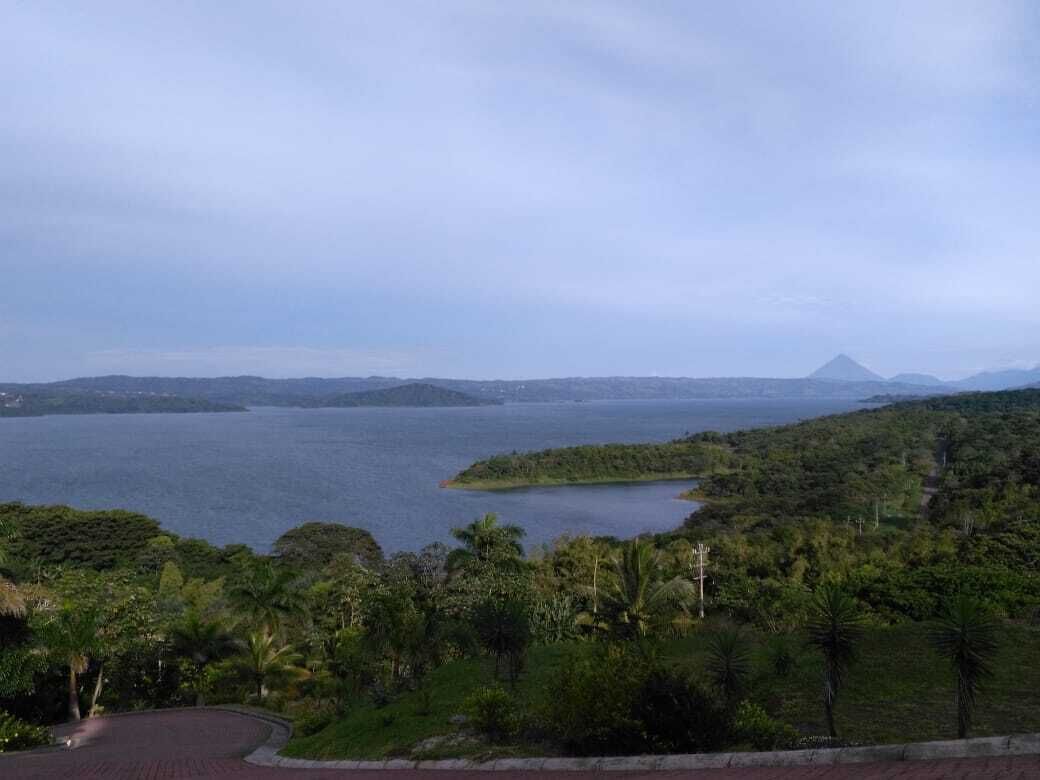 Eine Küstenlandschaft mit einem großen Gewässer, einer kleinen Insel und einem Berg in der Ferne.