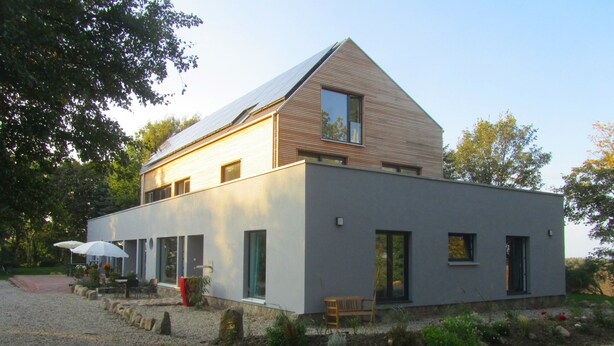 A modern two-story house with a sloped roof, large windows, and a gravel driveway. - Beltblick offers two large, comfortable apartments, located on Johannisberg (Fehmarn)