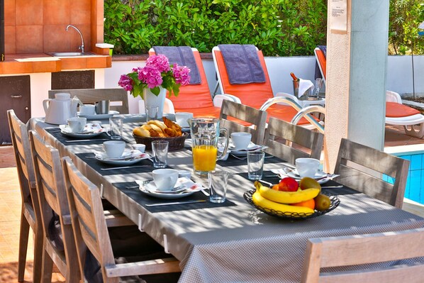 A breakfast setup with a table, chairs, and a poolside view. - Villa with private pool, BBQ and harbour view (2 kayaks/2 supboards) (Lozisca)
