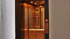 L’intérieur d’un ascenseur est doté d’une finition métallique, d’un écran numérique indiquant le numéro de l’étage et d’un panneau « interdiction de fumer ».