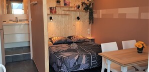 Una camera da letto con un letto, comodini, una testiera in legno, un tavolino con sedie e una finestra.
