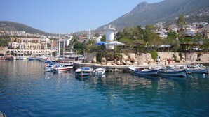 A marina with boats docked, a lighthouse, and a town with buildings in the background. - Town Centre Penthouse Apartment With Two Sea View Private Roof Terraces (Kalkan)