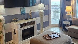 Un saló modern amb televisió de pantalla plana, ventilador de sostre, finestra gran amb vista i zona de seients acollidora.